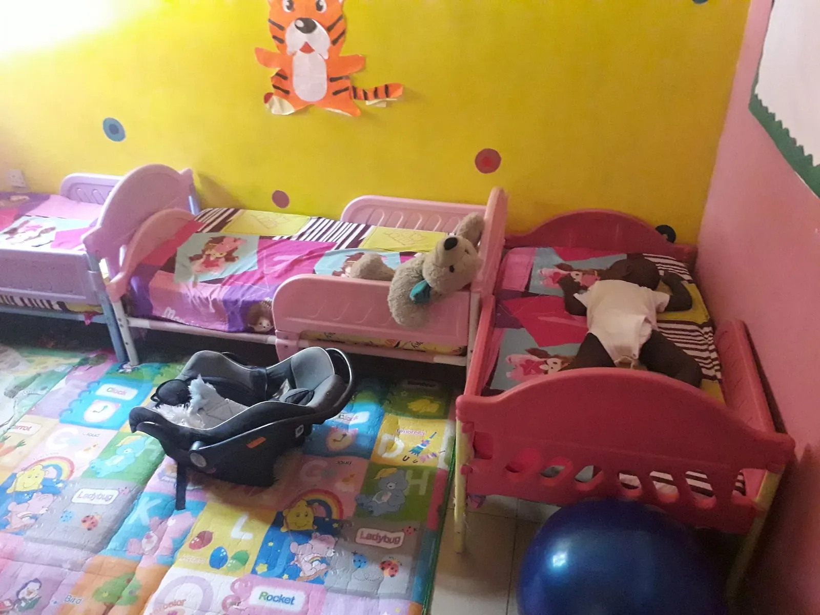 A bright room with small beds, soft toys and play mats for the youngest children
