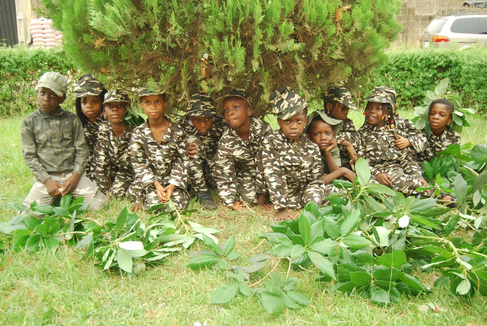 Young pupils dressed in camouflage outfits sitting together on the grass