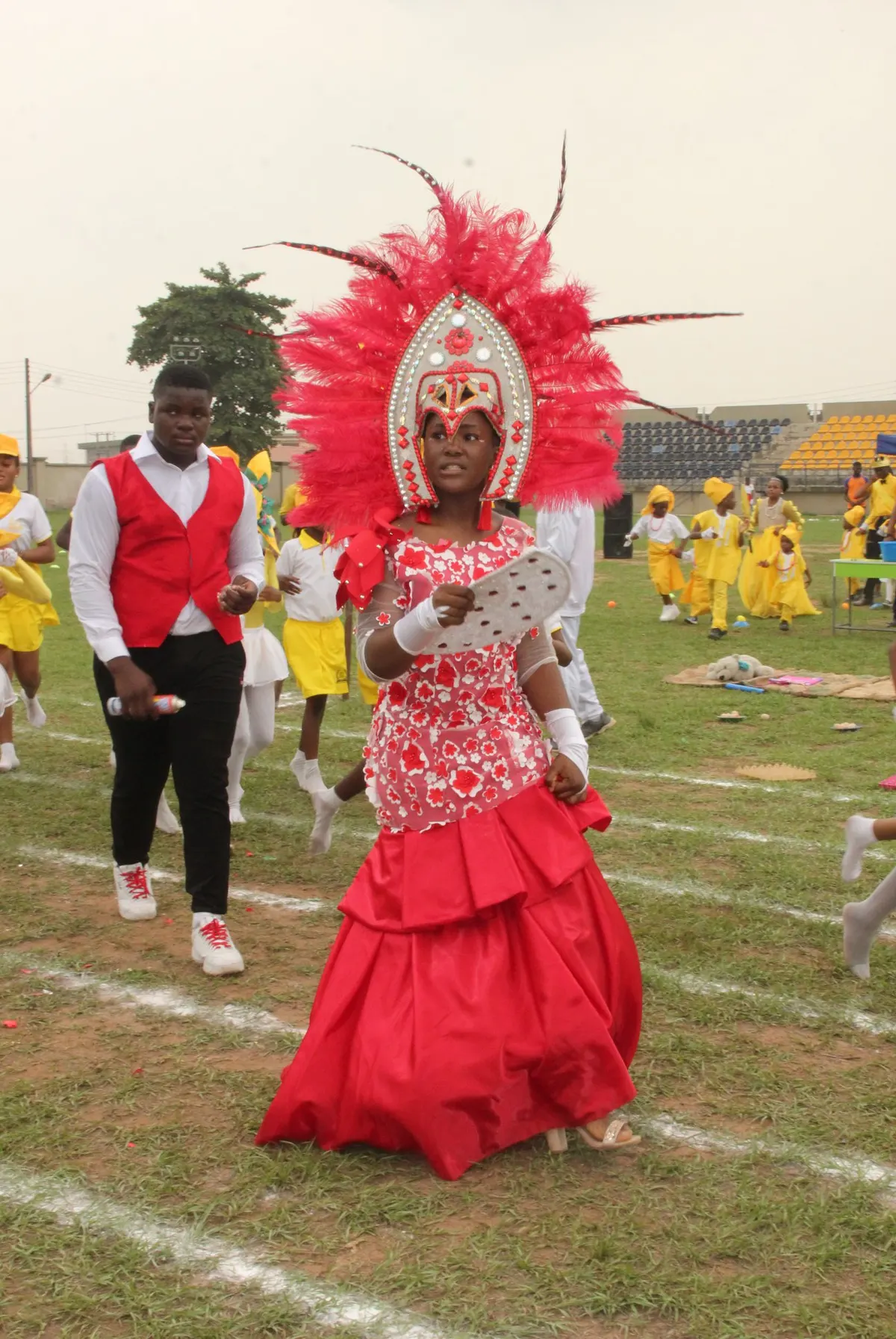 A participant in a red feathered carnival costume at sports day