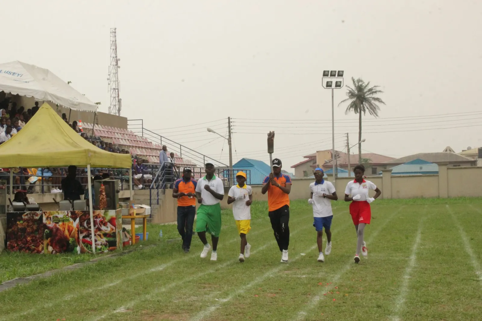 Pupils running in a race on a grass track during sports day
